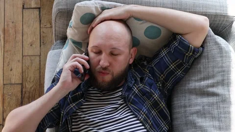 Man lying on the couch and talking on the phone. 库存影片 254907611