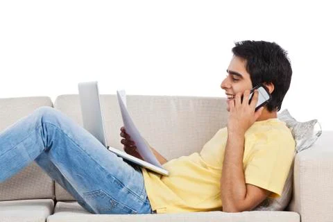 Man lying on a couch and talking on a mobile phone with holding a paper Stock Photos