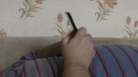 A man lying on the couch communicates on the phone via the internet Stock Footage 163080009