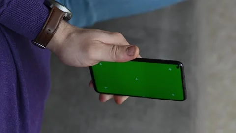Man lying on couch holding phone with green Chroma Key screen mockup, watching Stock Footage 262851436