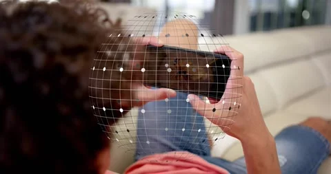 Man lying on couch holding phone, thumb tapping starting AR grid over phone Stockbeeldmateriaal 320627975