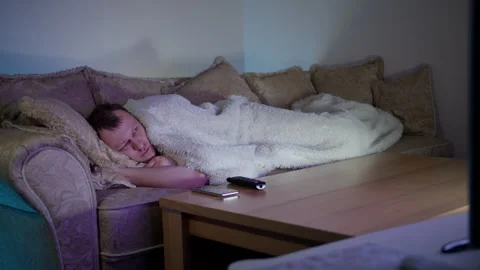 Man lying on the couch by the TV at night, evening light, copy space Stock Footage 161371981