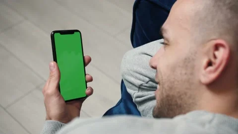 Man lying on couch using smart phone with chroma key green screen, internet Stock Footage 144079187