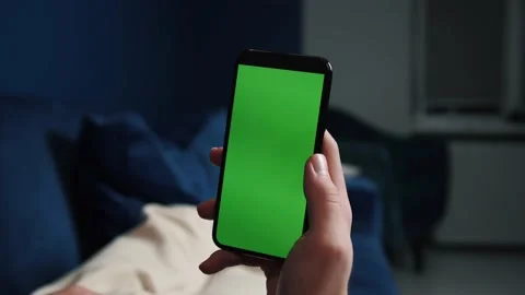 Man lying on couch using smart phone with chroma key green screen at night Stock Footage 144311245