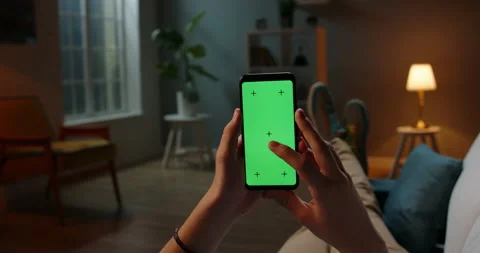 Man lying on couch using smartphone with chroma key green screen at night Stock Footage 140462060