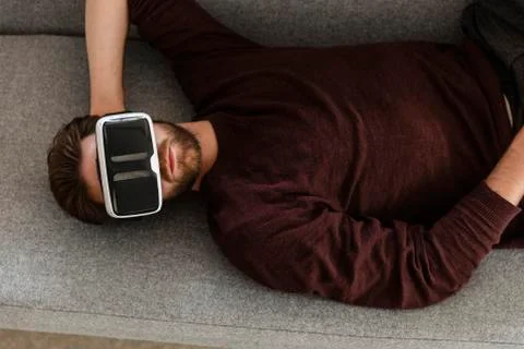 Man lying on the couch using Virtual Reality Glasses Stock Photos