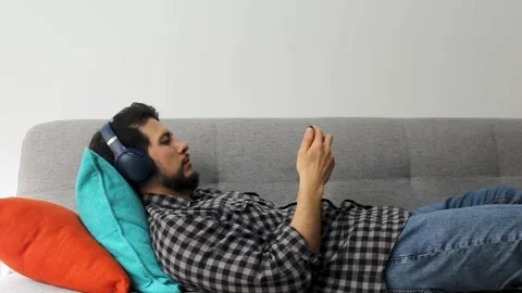 A man lying on a couch watching something on a smartphone Vídeo Stock 340583400