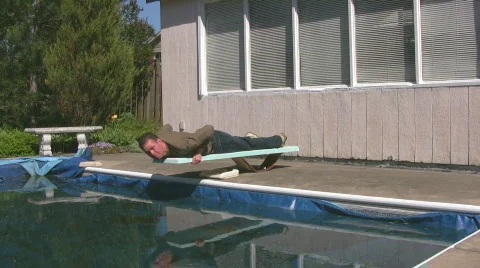 Man lying on diving board of winterized pool Stock Footage 545054