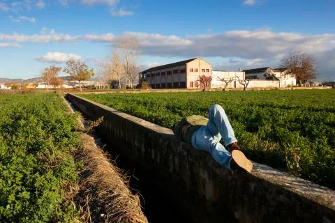 Man lying down and sleeping relaxed in a ditch wall. Stock Photos
