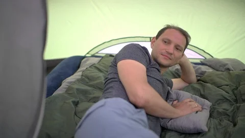 Man lying down closeup inside tent camp sleeping bag mattress resting Stock Footage 120609147