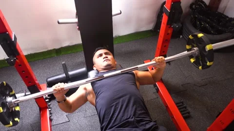 A man (lying down) doing a bench press seen from above Видео 146497746
