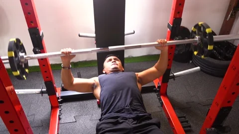 A man (lying down) doing a bench press in his personal gym Stock Footage 146498576