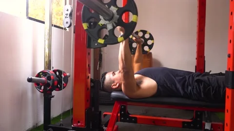 A man lying down doing the bench press seen in profile Video stock 146500588