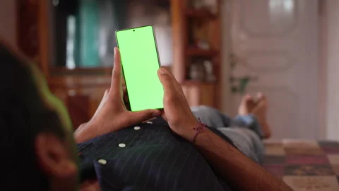 Man Lying Down at Home Holding Smartphone with Blank Green Screen Chroma Key. Stock Footage 338298849