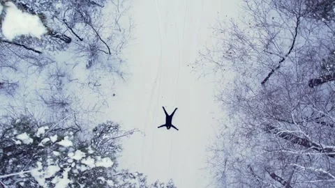 Man lying down making snow angel, top view Aerial view beautiful snowy winter Stock Footage 288779110