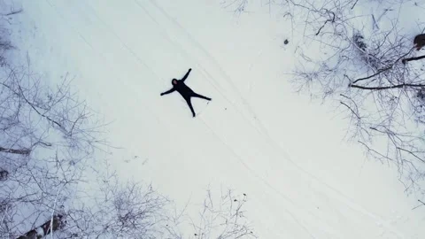 Man lying down making snow angel, top view. Outdoor activities and ecological Stock Footage 290252789
