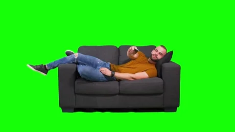 Man lying down on sofa and watching tv, green background Stock Footage 136369845