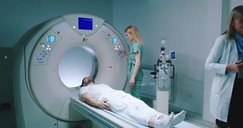 Man is lying down at TC scanner capsule. Medical pushes buttons and prerares for Stock Footage 243596289