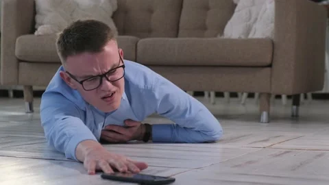 Man lying on the floor and holding his heart, trying to reach the phone Video stock 172199831