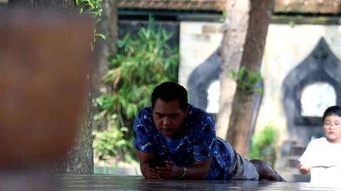 A man is lying on the floor playing with his cell phone Stock Footage 236619682
