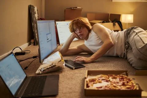 Man Lying on Floor Working with Computers in New Apartment Foto stock