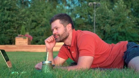 Man lying on grass and working on laptop Stock Footage 157334919