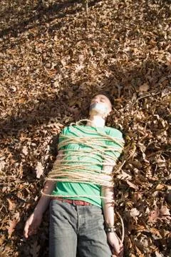 Man lying on the ground, bound in rope and with adhesive tape covering his mouth Stock Photos
