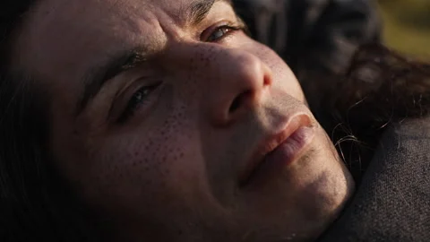 Man lying on the ground with a contemplative expression in cinematic sunlight Stock Footage 299973107