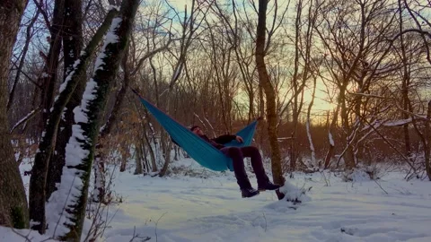 Man lying in hammock under the trees in the winter forest Stock Footage 146776257
