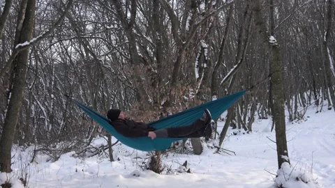 Man lying in hammock under the trees in the winter forest Stock Footage 146777419