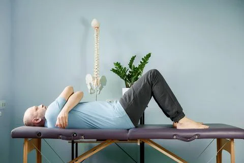 A man lying on the massage table in constructive rest postion, si joint pain Stock Photos