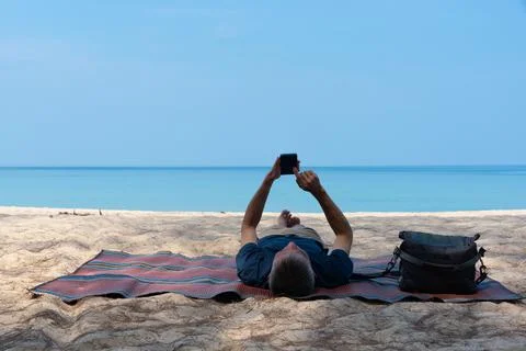 A man lying on a mat and using smartphone Stock Photos