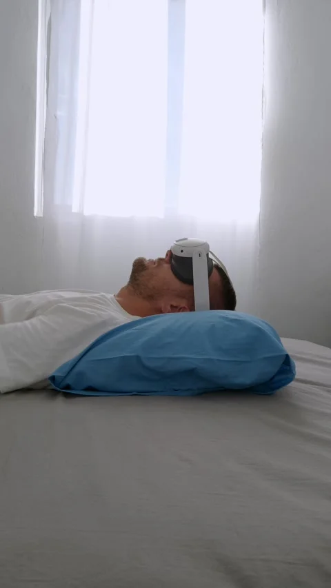 Man lying on pillow, using Virtual Augmented Reality headset at home. 動画素材 279759812