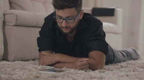 A man lying in the room looking at the tablet 動画素材 59328934