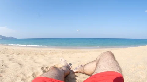 A man is lying on the sand and a plane is flying over him Stock Footage 123833089