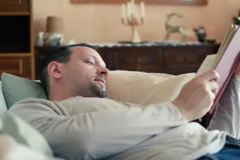 Man lying on sofa and reading book NTSC Stock Footage 10592739