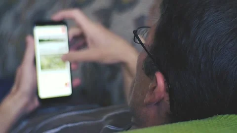 Man lying on sofa and using smartphone at home. Stock Footage 97332979