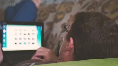 Man lying on sofa and using laptop at home. Stock Footage 97333018