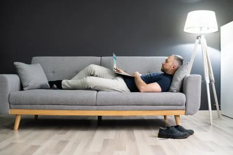 Man Lying In Sofa And Using Laptop Stock Photos