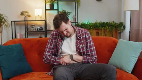 Man lying on sofa feeling sudden strong abdominal stomach ache gastritis problem Stock Footage 265342185
