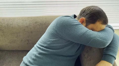 A man is lying on sofa with heads down and feeling very sad Stock Footage 226199231