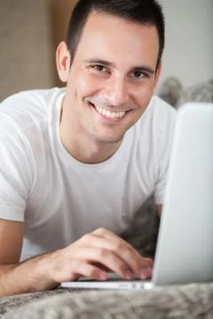 Man lying on the sofa with laptop Stock Photos