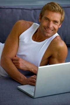 Man lying on sofa with laptop Foto stock