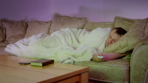 Man lying on the sofa at night in front of the TV with the remote control Stock Footage 310611663