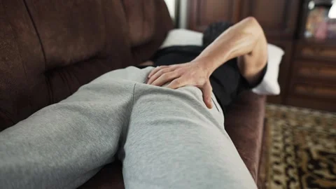 Man lying on the sofa scratching his ass Stock Footage 312473122