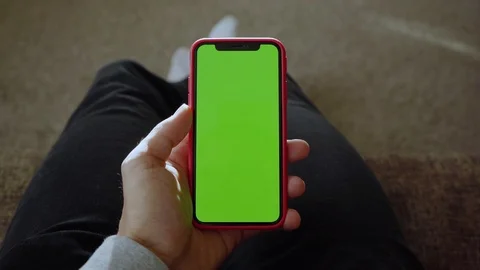 Man lying on sofa use vertical green screen phone at home living room device Stock Footage 118472660