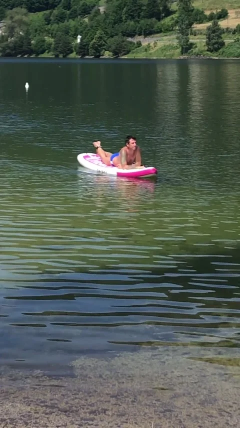 Man lying on a stand up paddle board is carried by the current Stock Footage 313364486