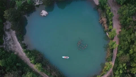 Man lying on SUP surfboard on blue lake surface Stock Footage 170412362