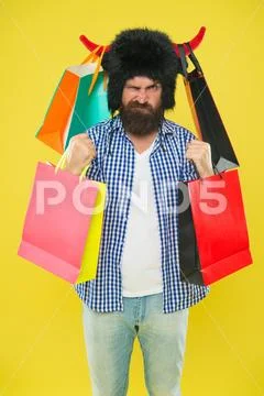 Man mad face wear hat bull with horns. Hipster shopping addicted or shopaholic Stock Photos