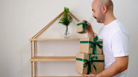 The man made a pine tree decoration from the shelf, he sets the surprise gift bo Vídeo Stock 142079782
